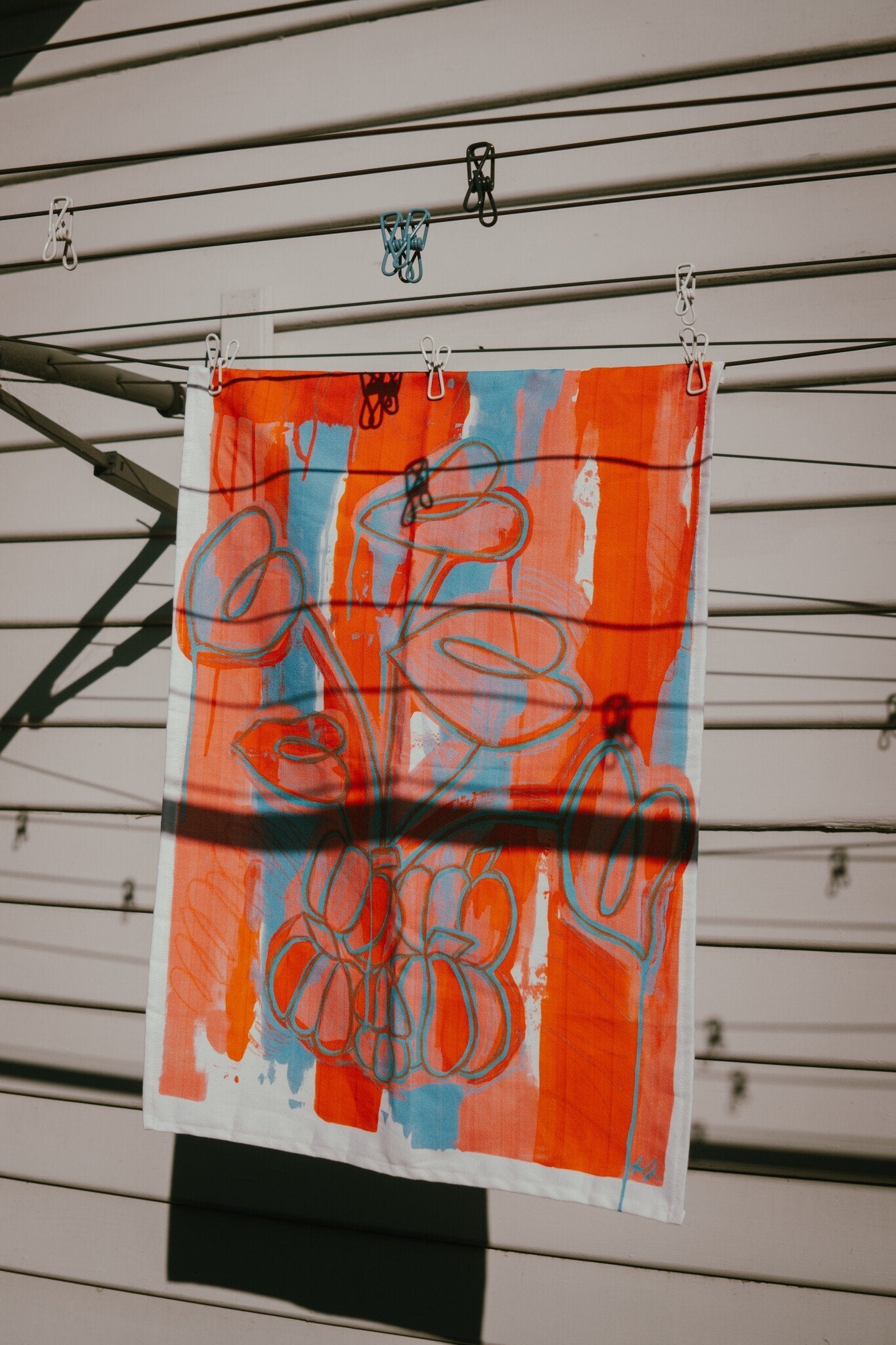 Printed tea towel by Melbourne artist Jay-Dee Pitcaithly hanging on a washing line