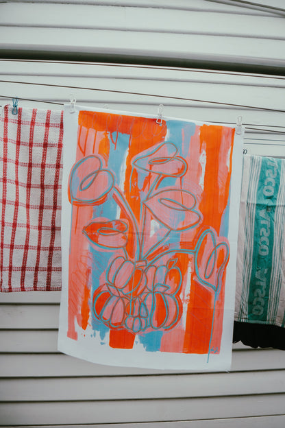 Tea towels by Jay-Dee Pitcaithly with floral design hanging on a washing line.