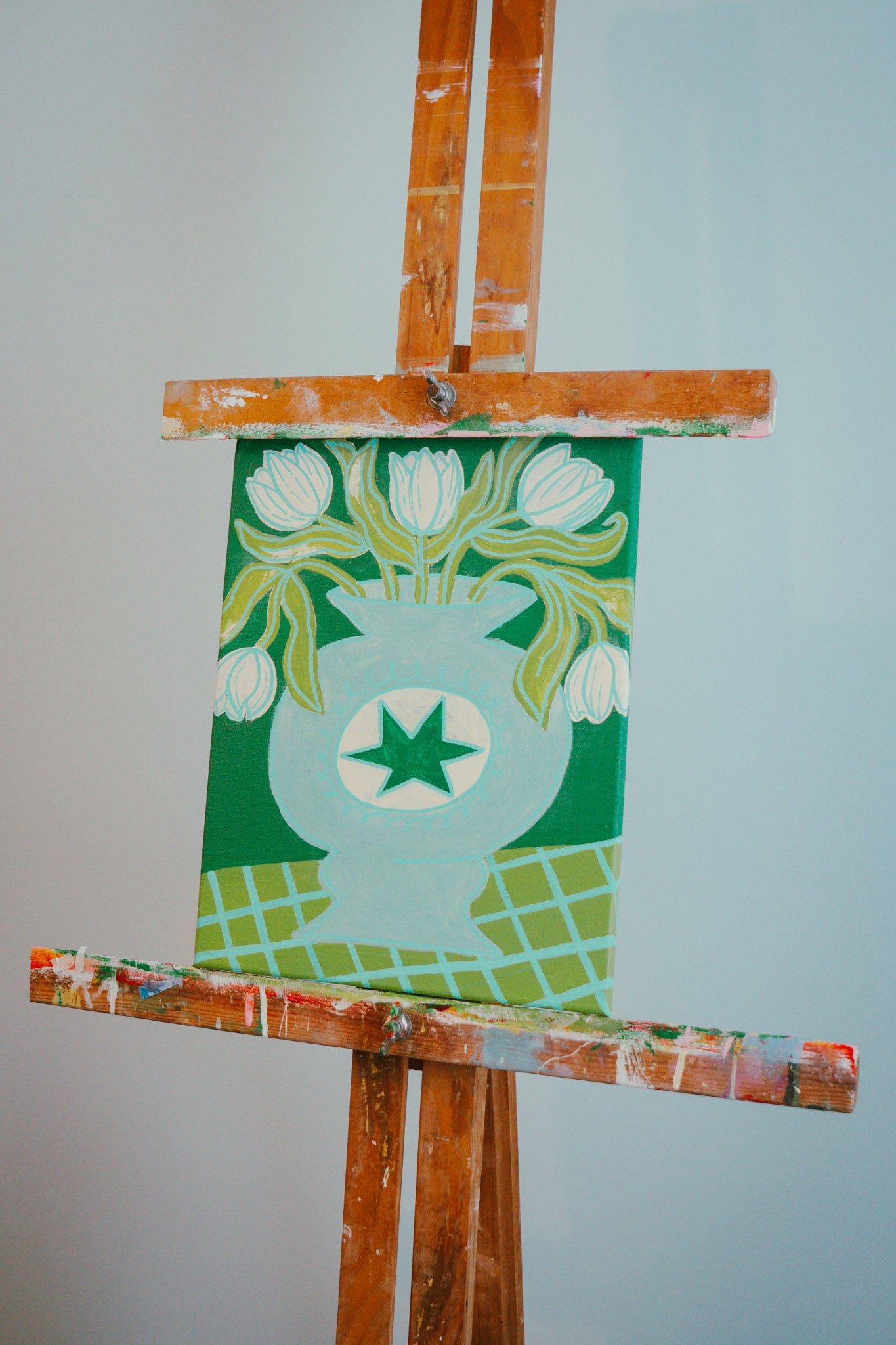 Wooden easel with a green, blue and cream original painting of tulips in a vase hand painted by Melbourne artist Jay-Dee Pitcaithly
